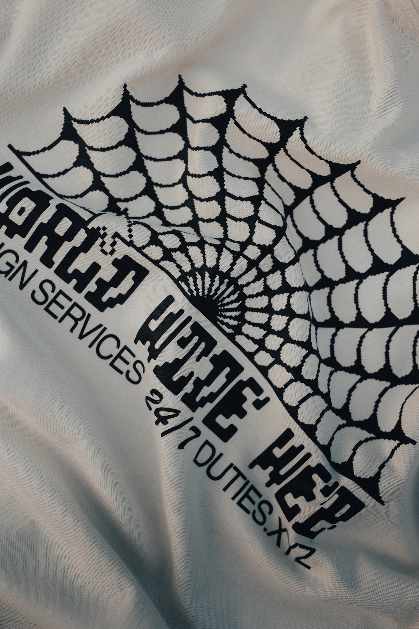 Close-up detail photo of an Ecru-colored Duties World Wide Web T-Shirt focusing on the big graphic print on the back.