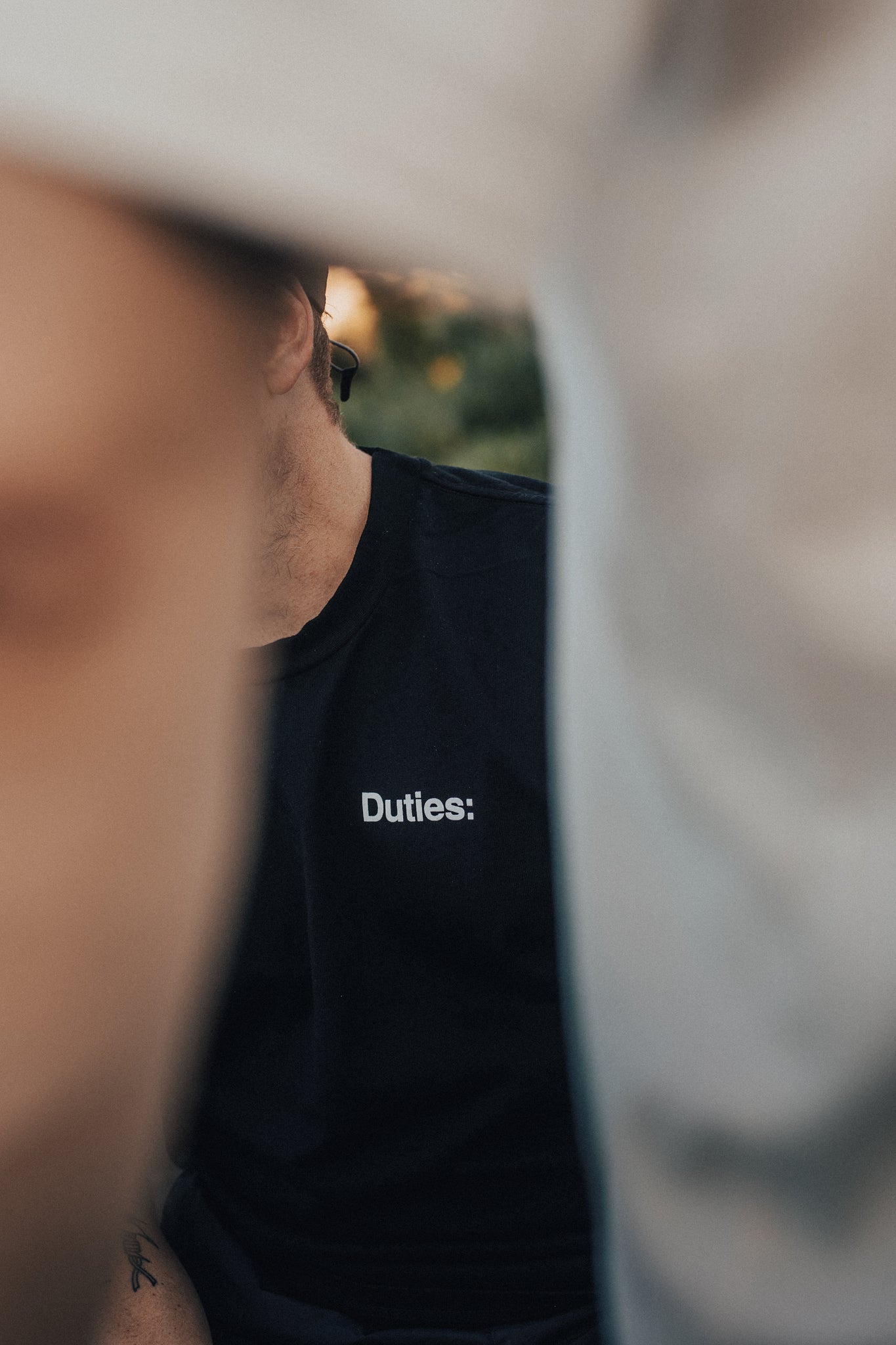 Detail photo of the Duties logo on the left chest of a black T-shirt.